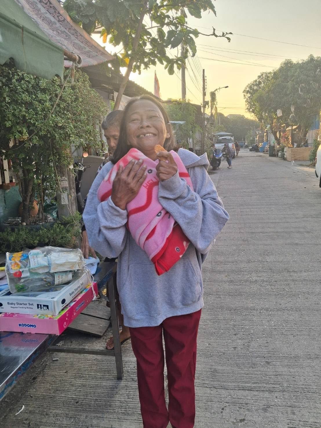 A community member holding donated baby supplies and blankets in the slum zone.