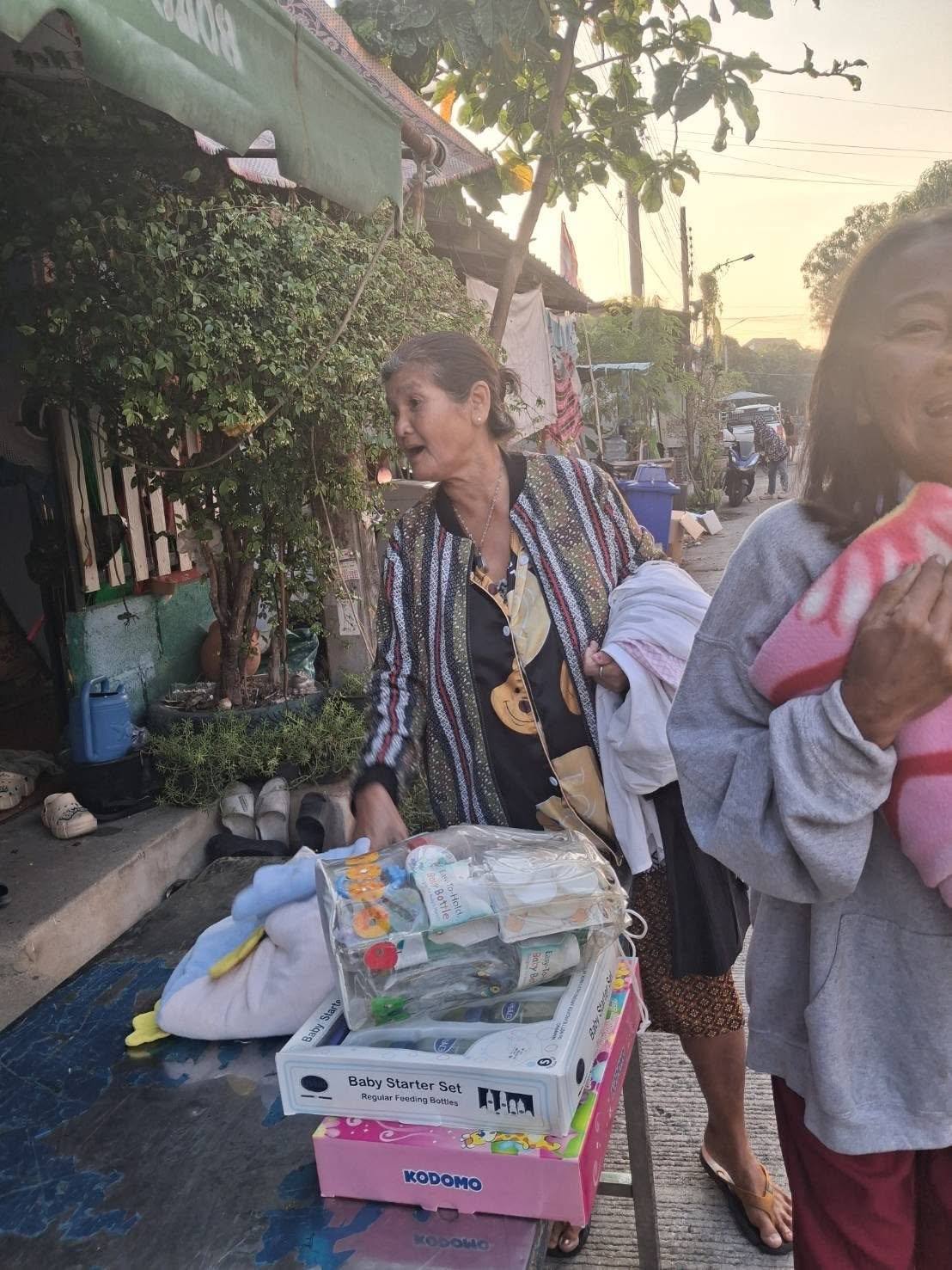 Another resident receiving a baby starter set and practical donated items in the community.