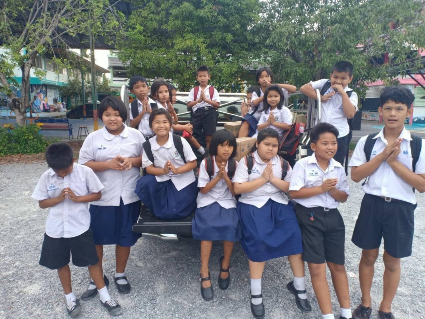 School children standing together with gratitude near community school transport support.