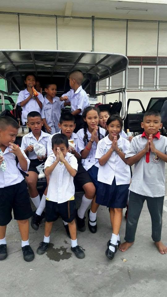 Children supported by the Thailand slum education sewa standing together near school transport.