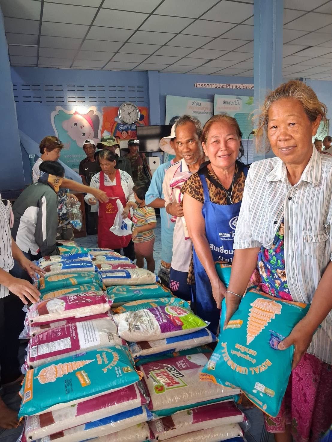 Community members receiving rice support inside a community center in Thailand.