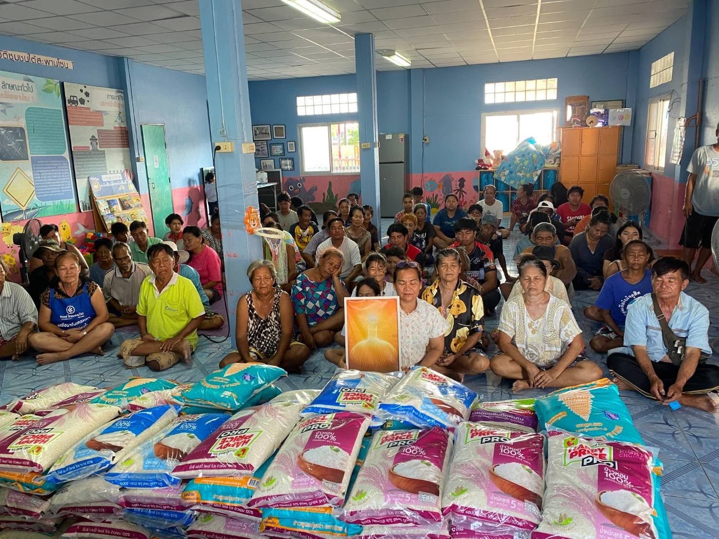 A large group of community members gathered with rice bags during the Thailand rice relief support activity.
